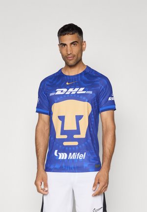 Tricou sportiv albastru, cu un grafic mare al feței unui leu auriu, logo-uri de marcă, mâneci scurte și un design dintr-un material texturat.