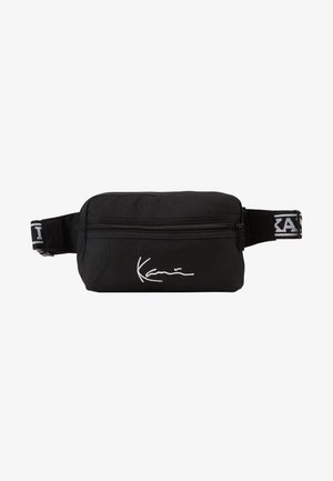 Black fanny pack made of durable fabric, featuring a zippered compartment, adjustable strap, and white signature logo on the front.