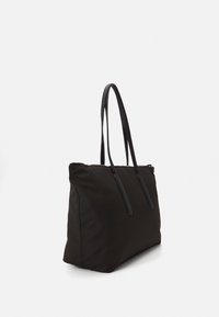 Černá nylonová taška přes rameno s dvěma dlouhými koženými uchy, obdélníkového tvaru, měkké struktury a s zipovým uzávěrem na vrchu.