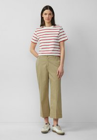 T-shirt a righe di colore bianco con strisce rosse; pantaloni larghi beige; sneakers bianche con dettagli grigi; tessuto morbido, design casual.