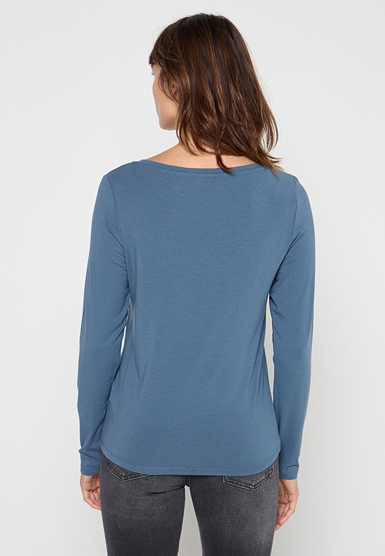Langemouwige blauwe shirt met een ronde halslijn. Gemaakt van zachte stof, heeft een slim fit en een licht gebogen zoom aan de achterkant.