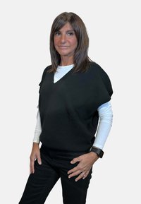 Maglione nero a scollo a V indossato sopra una camicia bianca a maniche lunghe, abbinato a pantaloni neri. Caratteristiche notevoli includono una vestibilità comoda e una texture sottile.