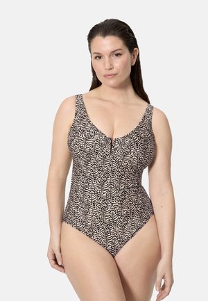 Mujer con el cabello largo y oscuro, vestida con un traje de baño de una sola pieza sin mangas con un patrón abstracto en negro y beige, de pie frente a un fondo claro.