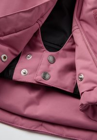 Interieur van een roze waterdichte jas, met een gladde textuur, drukknoopsluitingen en contrasterende zwarte voering voor functionaliteit en stijl.