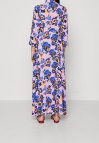 Maxi sukienka z lekkiego, kwiatowego materiału. Posiada błękitne, żółte i różowe odcienie, trzyczwarte rękawy oraz luźny krój.