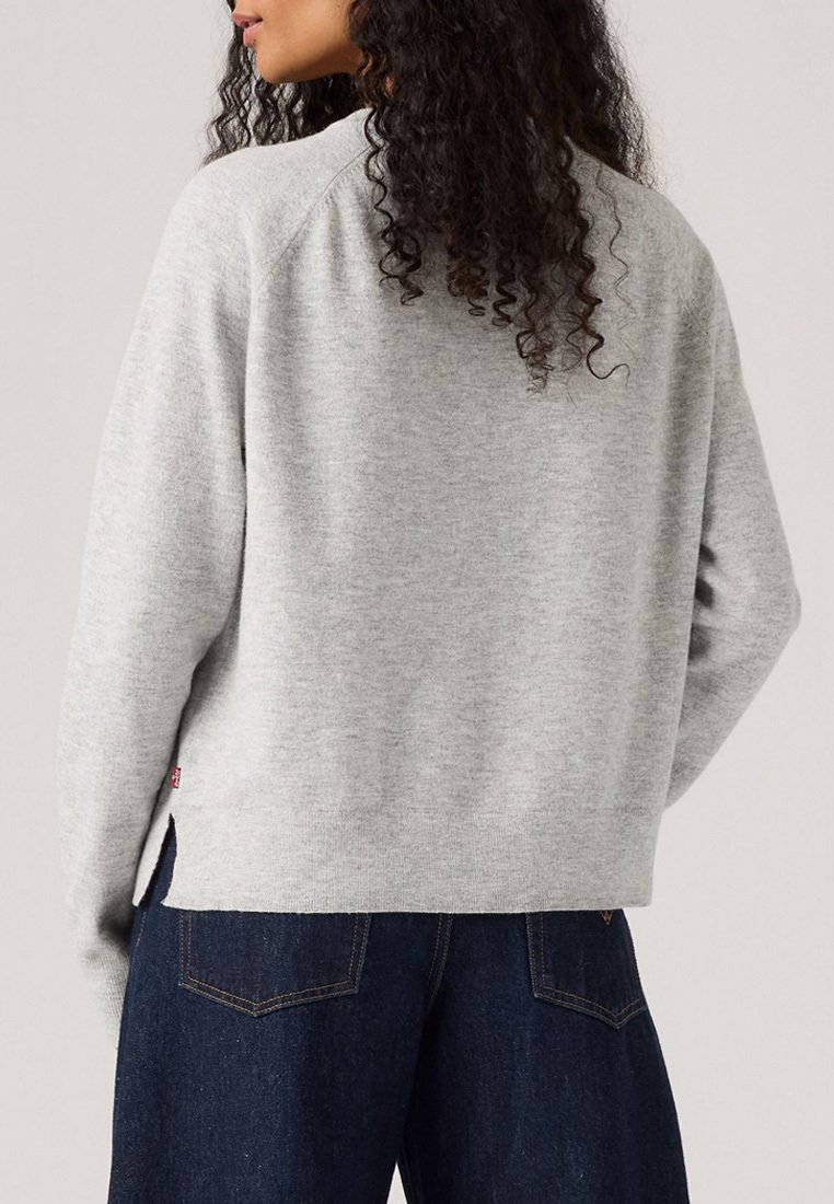 Maglione grigio a maniche lunghe con maniche raglan, polsini e orlo a costine. Presenta una fessura laterale nella parte inferiore e un piccolo cartellino con il logo sul lato sinistro.