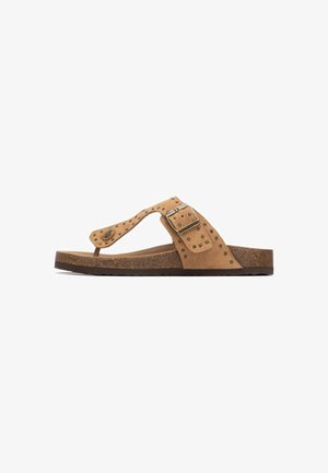 Chancla de gamuza marrón con una amplia correa que presenta detalles con tachuelas y una hebilla metálica, descansando sobre una suela exterior marrón texturizada.