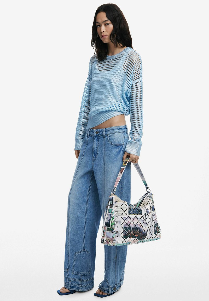 Helleblaue Mesh-Pullover, weit geschnittene hellblaue Jeans und eine gemusterte Schultertasche mit bunten Akzenten und gewebter Struktur.