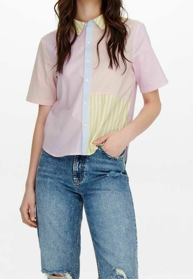 Chemise à col à manches courtes présentant un design à rayures pastel, avec des sections en rose, jaune et bleu clair, associée à un short en denim déchiré.