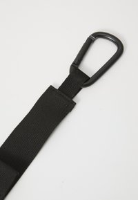 Sangle noire en nylon avec un clip de mousqueton en métal attaché, présentant une surface texturée et des coutures renforcées à l'extrémité supérieure.