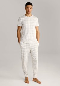 Ensemble de pyjama en coton blanc avec un motif géométrique. Haut à manches courtes et pantalon à taille élastique avec poignets. Texture douce.