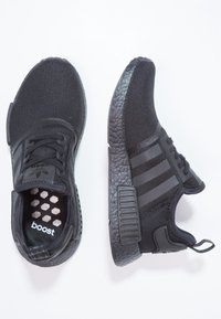 Schwarze Sportschuhe mit Obermaterial aus Netzgewebe, ausgeprägter texturierter Sohle, drei gestreiftem Design und gepolstertem Fu�ßbett mit "boost"-Branding.