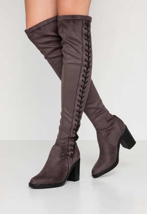 Bottes grises au-dessus du genou en tissu doux avec un bout pointu, un talon bloc et un laçage décoratif noir sur le côté extérieur.