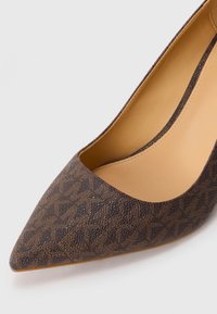 Chaussure à talon haut brun à bout pointu en matériau synthétique texturé, présentant un motif géométrique subtil et un intérieur beige lisse.