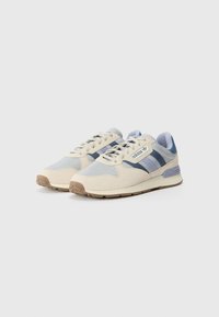 Sneakers with a cream upper, blue suede accents, and mesh panels. Features include a rubber sole and three blue stripes on the side.