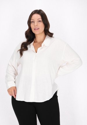 Camicia bianca con bottoni realizzata in tessuto leggero, con colletto classico, maniche lunghe e una vestibilità rilassata con fessure laterali.