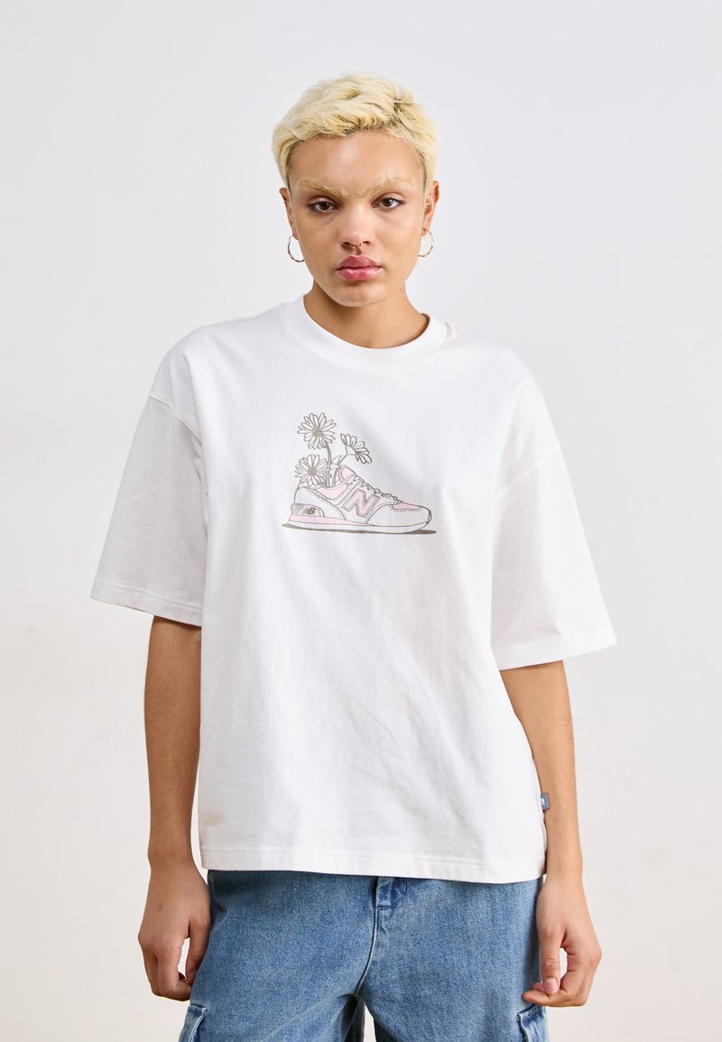 T-shirt oversized en coton blanc avec un graphique de basket et de fleurs, manches courtes et col rond. Pantalon en denim bleu texturé.