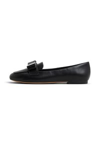 Chaussure plate en cuir noir avec un petit talon et un grand nœud décoratif sur le dessus, vue de côté sur fond blanc.