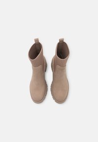 Brązowe botki za kostkę o gładkim zamszowym wykończeniu, żebrowanym dzianinowym kołnierzu, okrągłym nosku i teksturowanej gumowej podeszwie. Dwie pętle z tyłu.