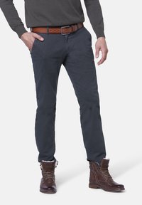 Grå bomullsblandade byxor, slim fit, med fem fickor. Bärs med ett brunt läderbälte och bruna snörade ankelstövlar.