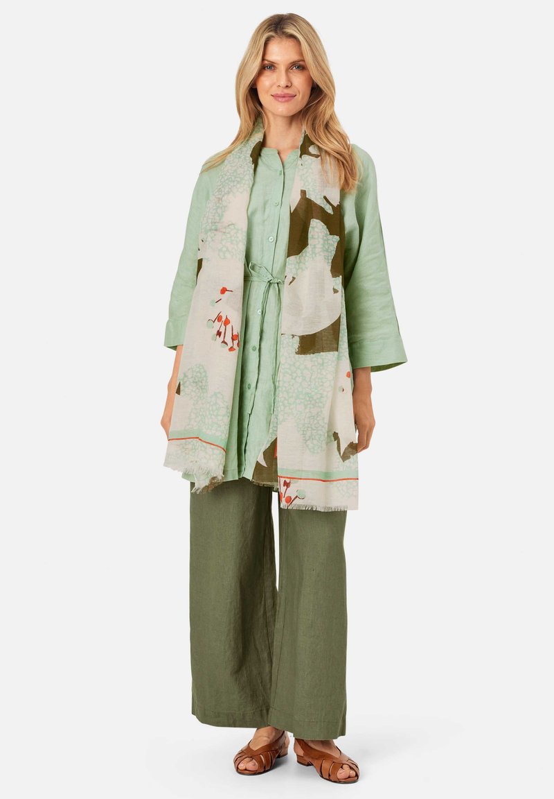 Light green linen shirt, olive green wide-leg pants, and a patterned scarf with greens and reds; relaxed fit, textured fabric, and fringe detail.