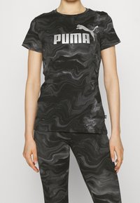 Camiseta deportiva de manga corta con patrón de mármol negro, que presenta un destacado logo plateado "PUMA" en el frente. Textura de tela estampada.
