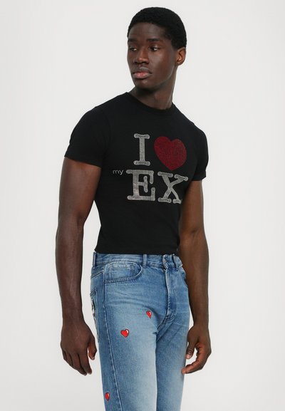 Tricou negru cu mânecă scurtă, având designul "I ❤️ EX" din strasuri; asortat cu blugi ușor albaștri, cu aplicații în formă de inimă roșie.