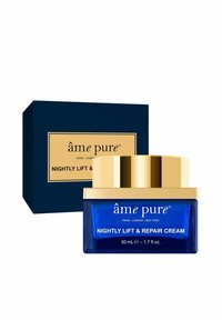 Nattlyft och reparationskräm i en blå glasburk med guldaccenter; förpackad i en marinblå låda med creamfärgad text och logotyp.