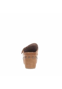 Zapato de ante marrón sin cordones, con punta redondeada, tacón elevado y tachuelas metálicas decorativas a lo largo del costado. Acabado suave y texturizado.