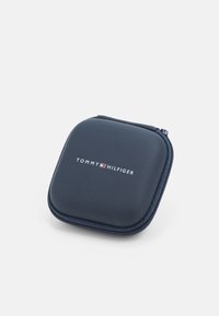 Custodia rigida navy con chiusura a zip, caratterizzata dal logo "TOMMY HILFIGER" in bianco. Esterno liscio con una leggera finitura opaca.
