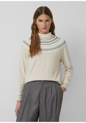 Helles beiges Sweatshirt mit hohem Kragen, das mit komplizierter schwarzer Stickerei um den Kragen sowie dekorativen gemusterten Bündchen versehen ist.