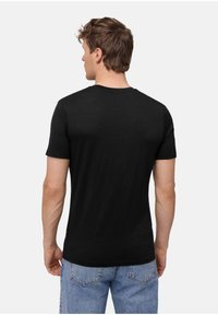 Schwarzes Kurzarm-T-Shirt mit rundem Halsauschnitt, glatter Textur und minimalistischem Design, kombiniert mit hellblauen Jeans.