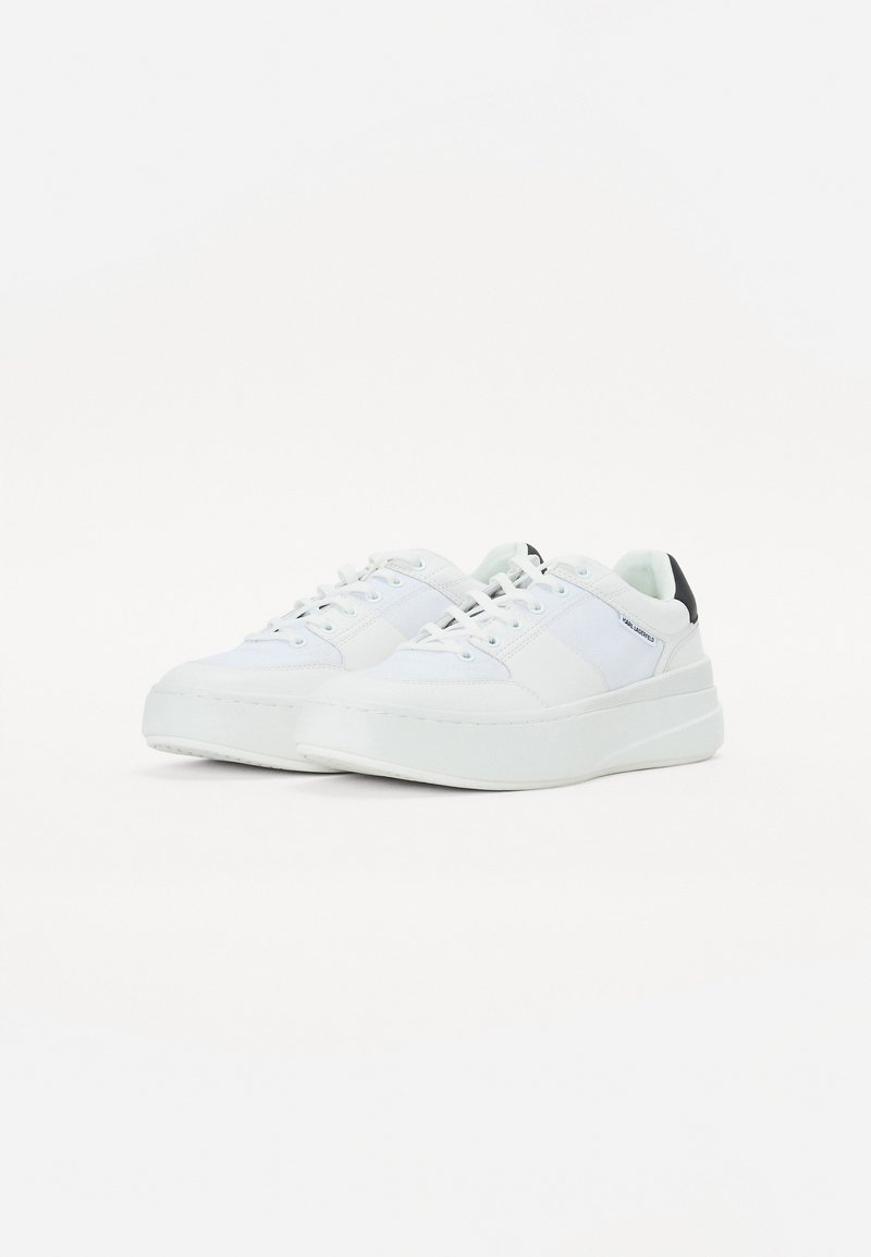 Baskets blanches avec une tige en cuir lisse et texturé, des lacets plats, une semelle plateforme et un accent noir au niveau du talon.