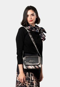 Borsa nera a tracolla con un pattina a piega decorata. Caratterizzata da una finitura in pelle vegana e una tracolla. Gli accessori includono testo e design ricamati.
