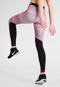 Leggings de corte alto en negro con un patrón geométrico texturizado en rosa, que presentan una cinturilla sólida y acentos de contraste a lo largo de los lados.