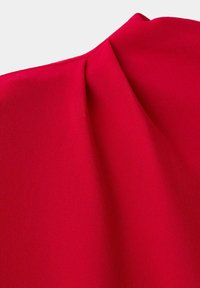 Gros plan sur un tissu rouge vif avec un détail plié créant de doux plis sur une surface lisse.