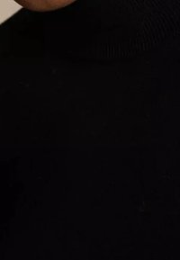 Pull noir à col roulé avec une texture côtelée, présentant une coupe ajustée et un col haut. Accent sur l'encolure et le détail du tissu.