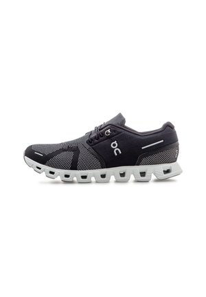 Chaussure de sport noire et grise avec semelle blanche coussinée comportant des poches d'air, design à lacets et tige en mesh respirant.