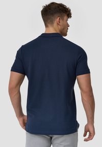 Granatowa koszulka polo z krótkimi rękawami, wykonana z miękkiej bawełny, z prążkowanym kołnierzykiem, minimalistyczny design i prostym wykończeniem dołu.