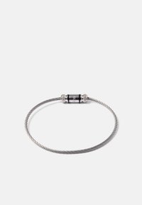 Bracelet en fil métallique argenté torsadé avec un fermoir magnétique cylindrique noir et argent gravé au nom de la marque.