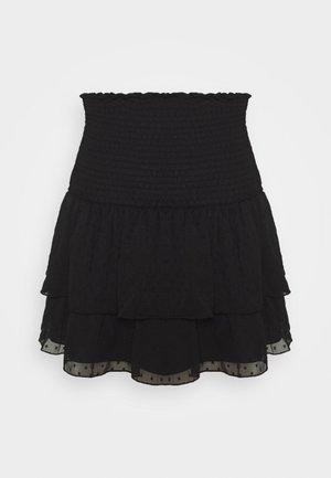 Jupe mini noire à plusieurs couches avec une taille smockée et un subtil motif de points texturés, présentant un ourlet fluide à double niveau.