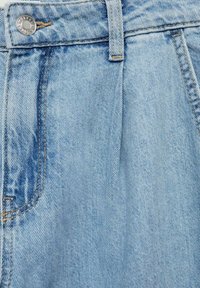 Gros plan sur un jean en denim bleu clair montrant la taille, la boucle de ceinture, le bouton et la poche avant avec des détails de couture visibles.