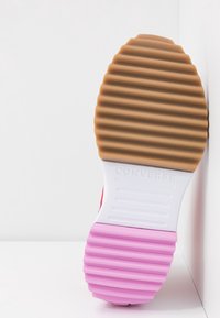 Semelle de chaussure Converse rouge avec un motif texturé. Présente des rayures en caoutchouc alternant entre beige et rose, avec "CONVERSE" embossé en blanc.