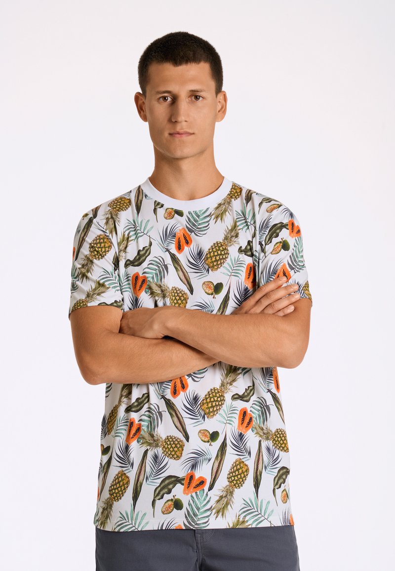Vit t-shirt med kort ärm som har ett färgglatt tropiskt frukt- och lövmönster i gröna, orange och bruna nyanser.