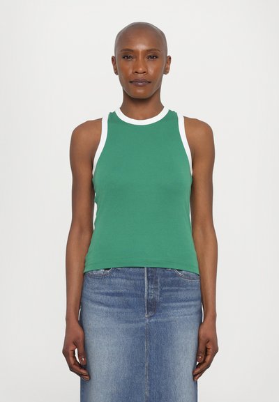 Haut sans manches vert avec des bordures blanches, fabriqué en coton doux. Présente un design ajusté et une texture lisse, associé à une jupe en denim.