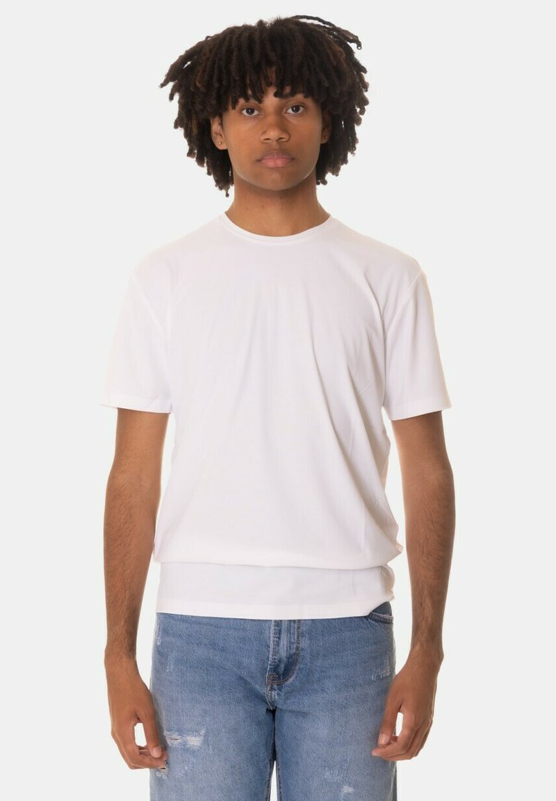 T-shirt bianco a maniche corte realizzato in tessuto liscio, con scollatura rotonda e vestibilità rilassata. Abbinato a jeans blu con effetto consumato.