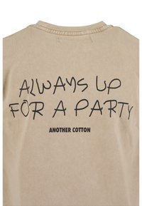 Béžové bavlněné tričko s krátkými rukávy, na zádech černý nápis "VŽDY PŘIPRAVEN NA PÁRTY" a "DALŠÍ BAVLNA".