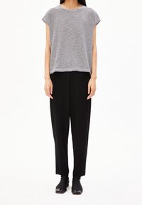 Black loose-fitting pants paired with a gray and white striped short-sleeve top. The top has a rounded neckline and a relaxed silhouette.