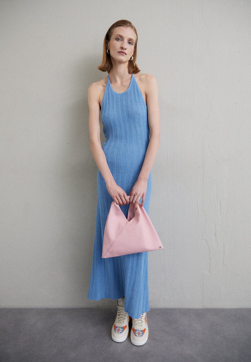 Robe halter bleu côtelé avec une silhouette ajustée, sac à main rose texturé au design angulaire, et baskets blanches à motifs.
