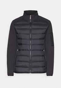 Veste hybride noire avec devant matelassé, manches en tissu doux, fermeture éclair complète à l'avant, deux poches latérales zippées, et une poche zippée sur le bras gauche.
